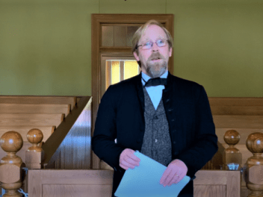 Josh Williams dressed in period wear reading the Declaration of Independence