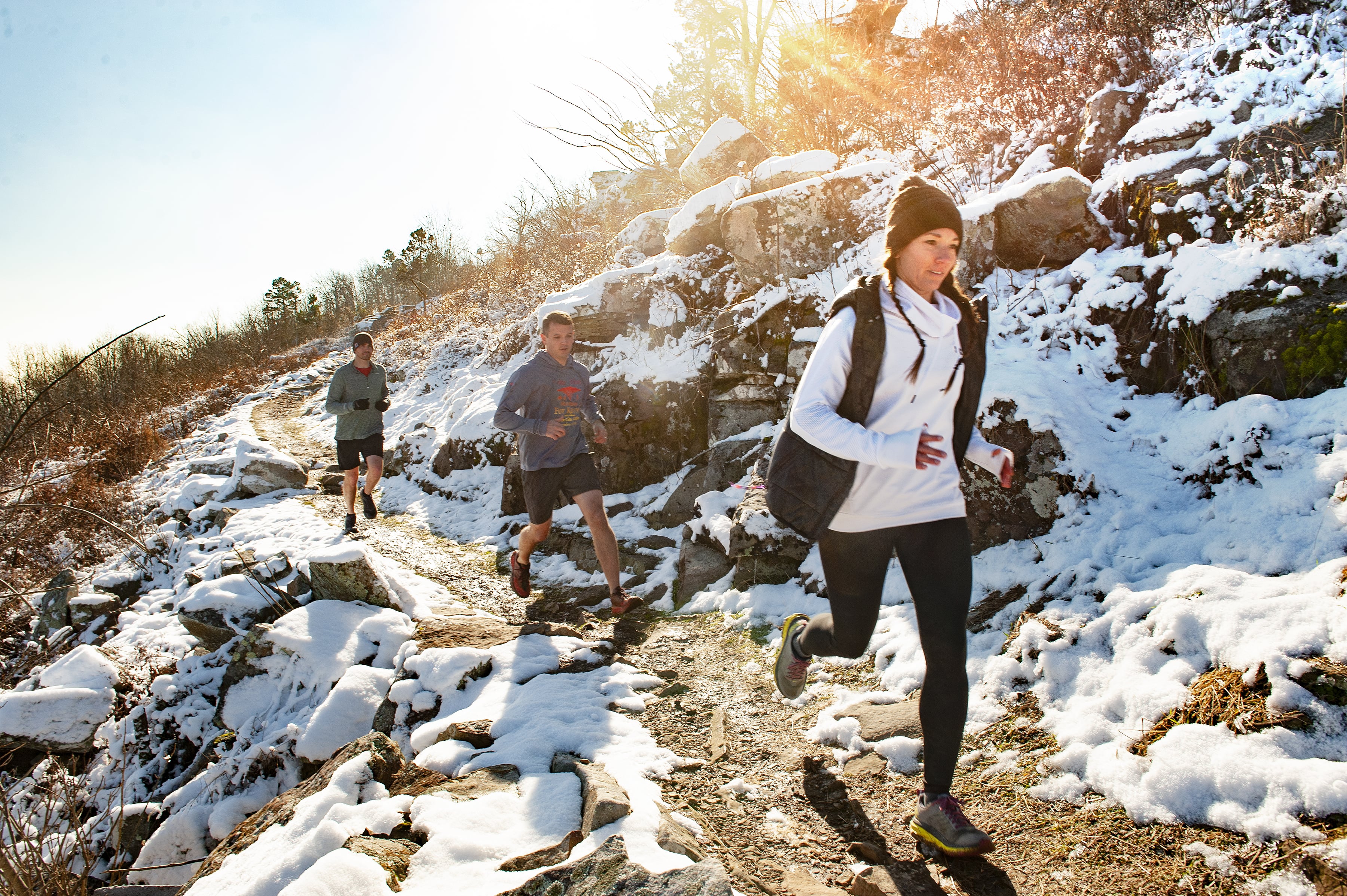Three people running on the Monument Trails in the snow during the winter at Mount Nebo State Park