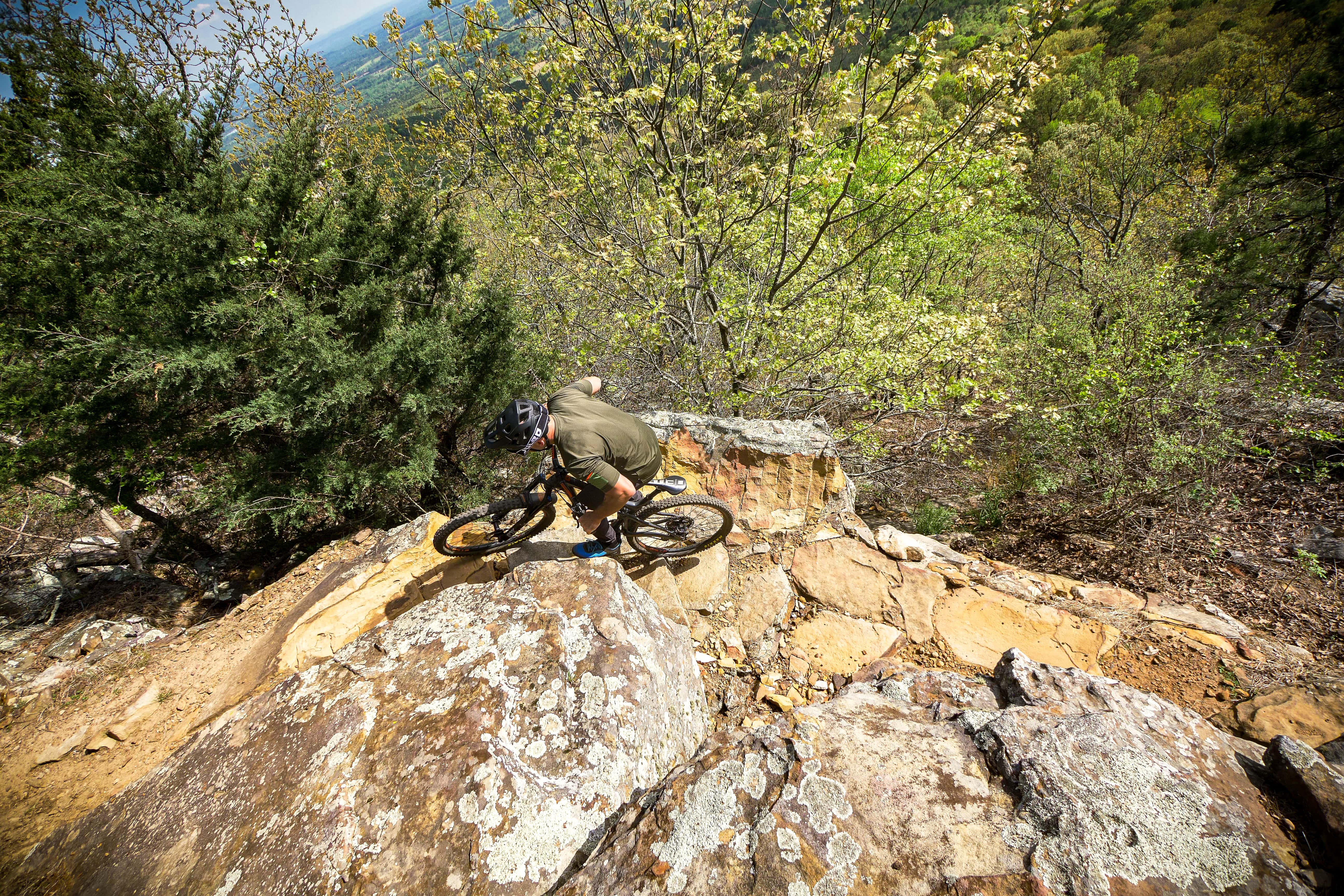 A mountain biker navigating a narrow rocky pathway on the Monument Trails at Mount Nebo State Park