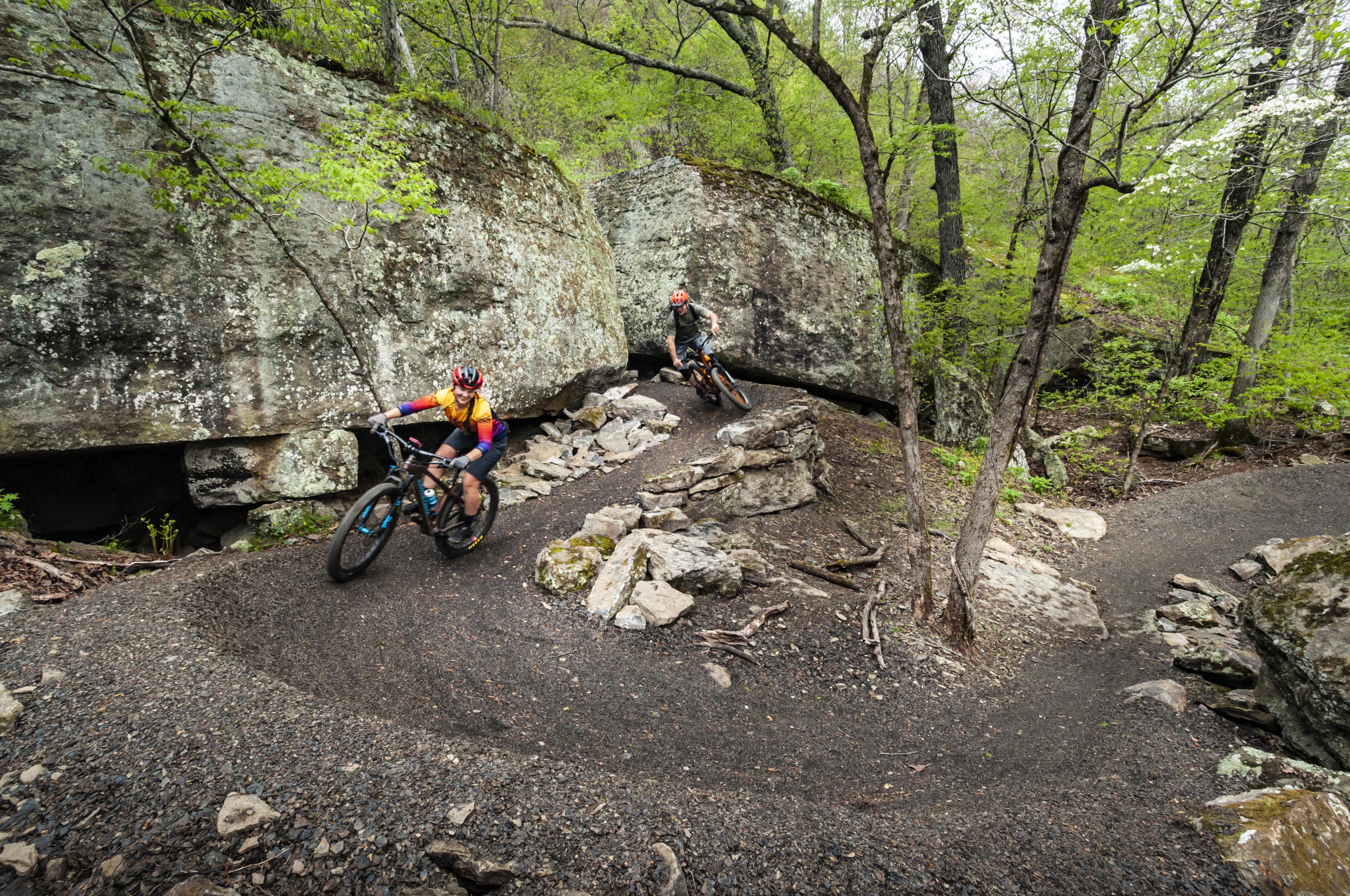 Two mountain bikers coming around a turn on the Monument Trail at Devil's Den State Park