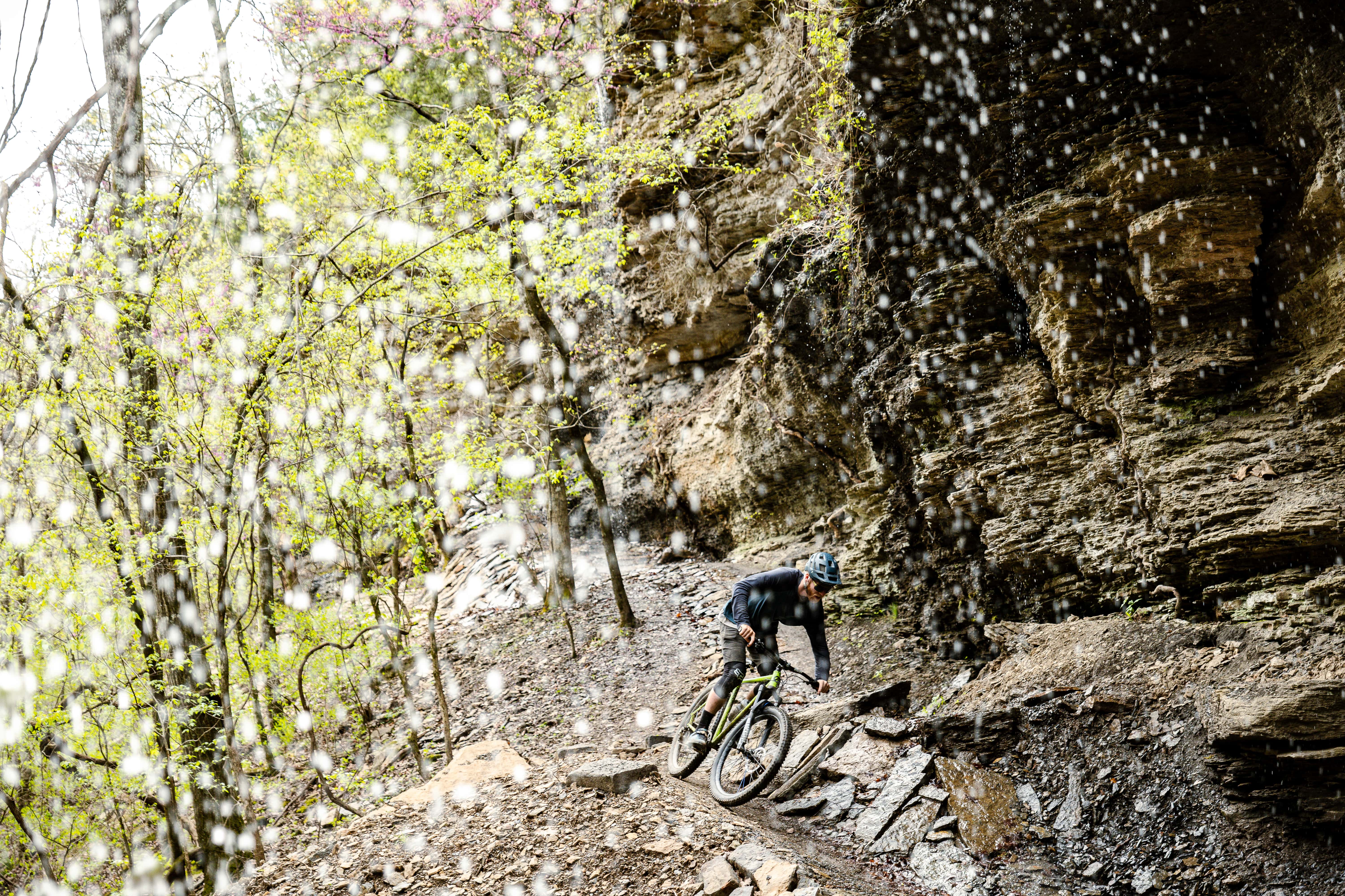 A mountain biker riding the Monument Trails in the rain at Devil's Den State Park