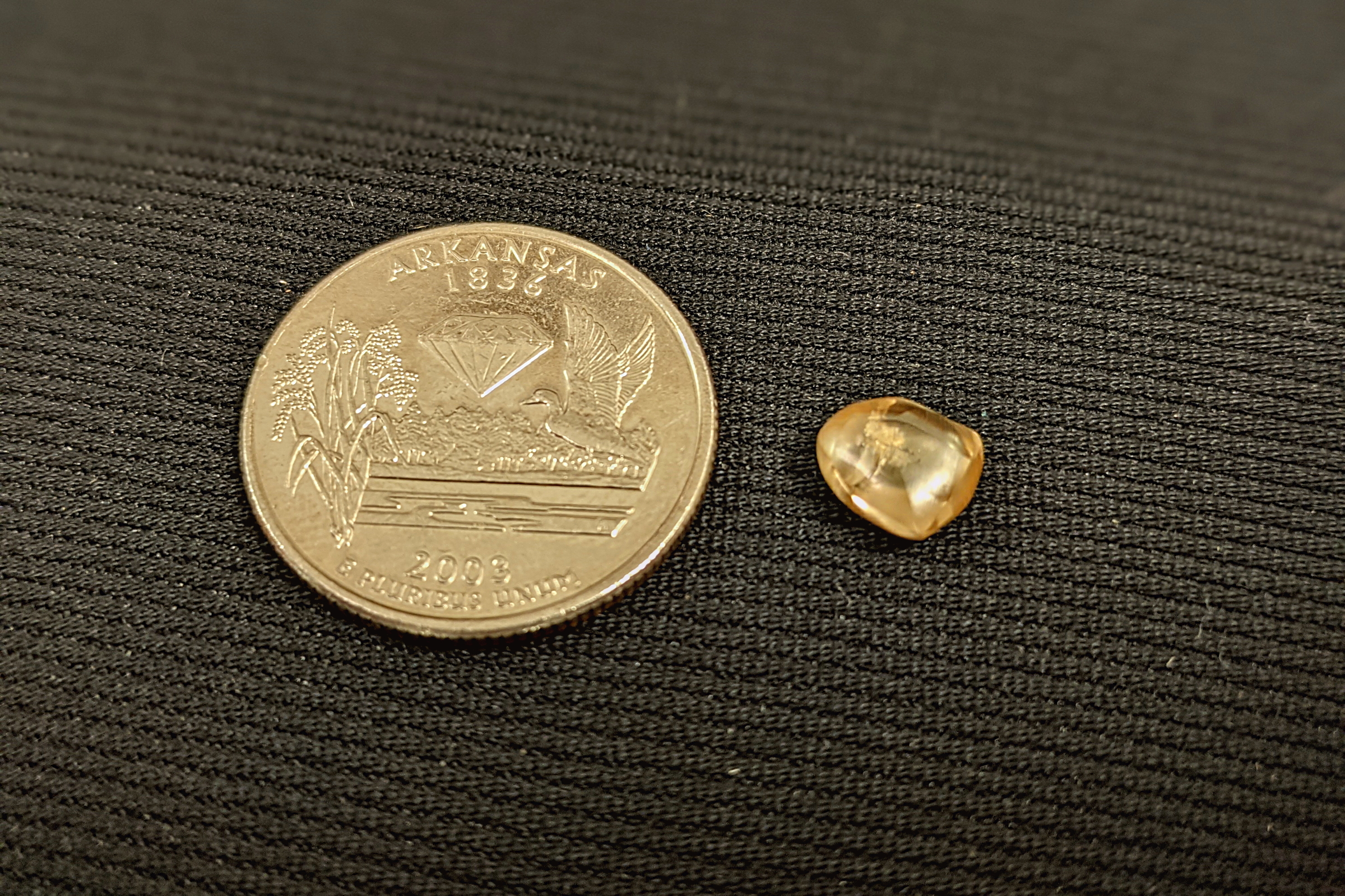 2.20 carat yellow diamond sitting next to a quarter for scale
