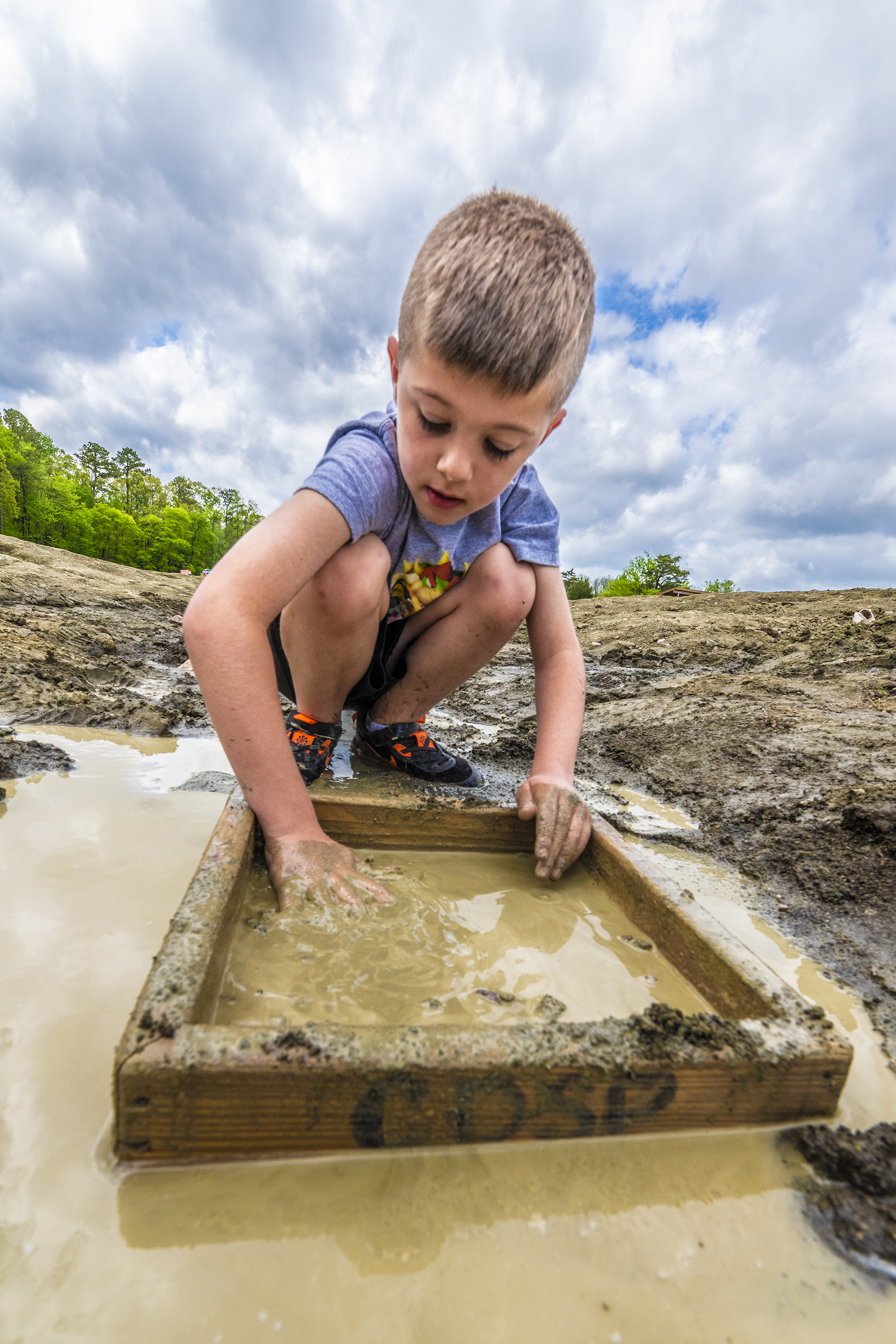 Child wet sifting through the mud to find a diamond at the Crater of Diamonds search field