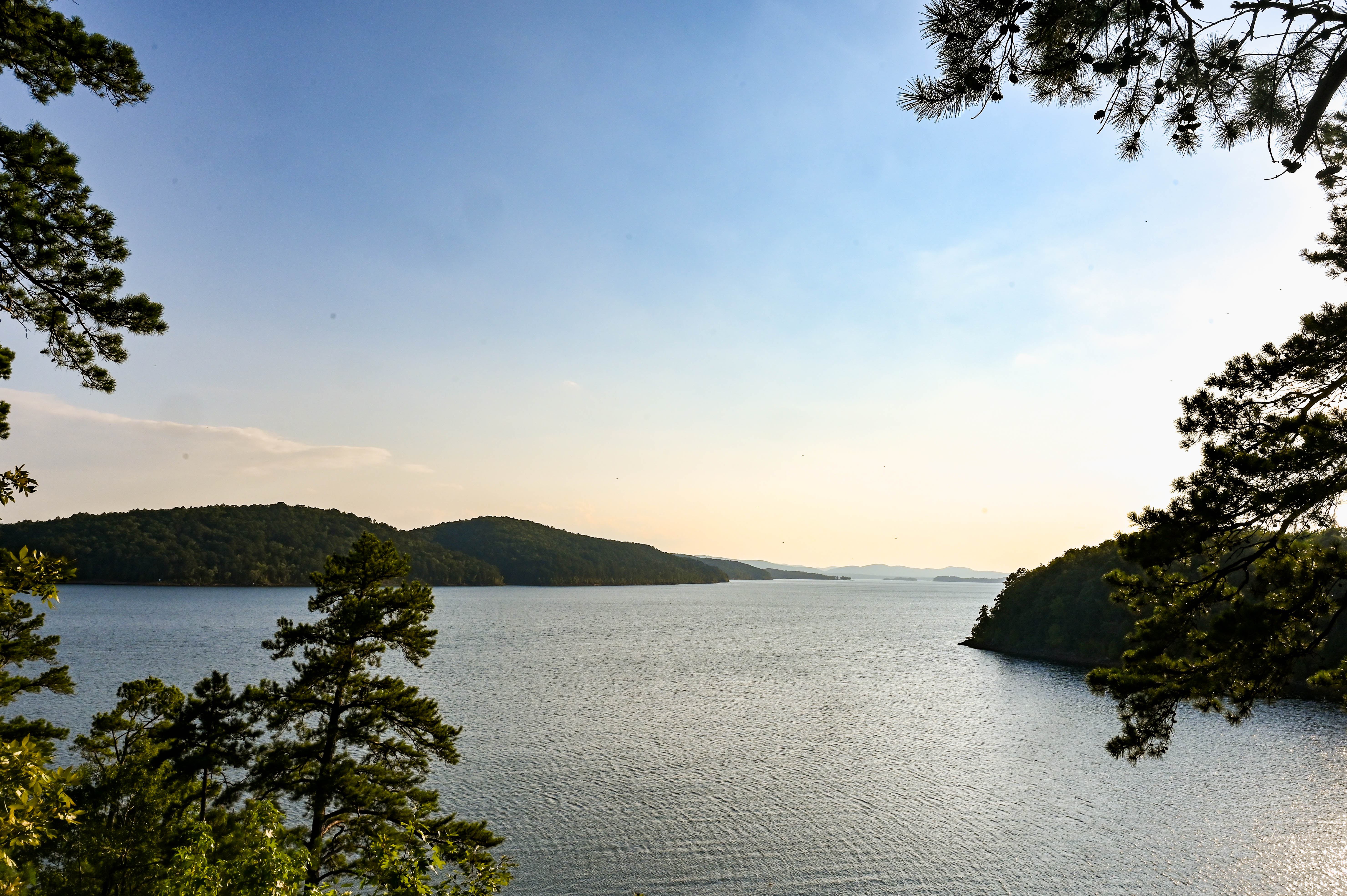 A vast view of the lake surrounded by wooded areas 