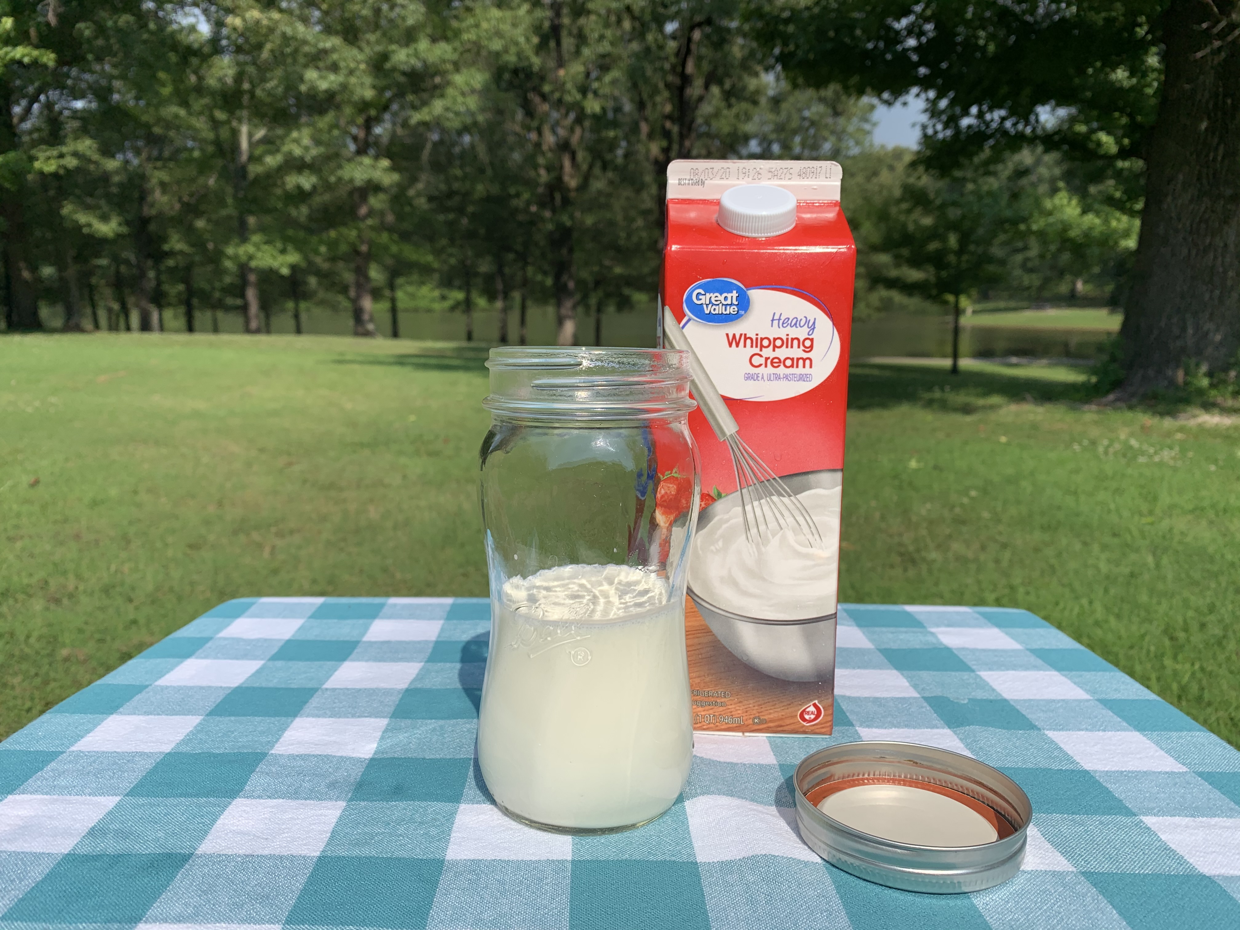 On the table there is a mason jar that is filled halfway with cream.)