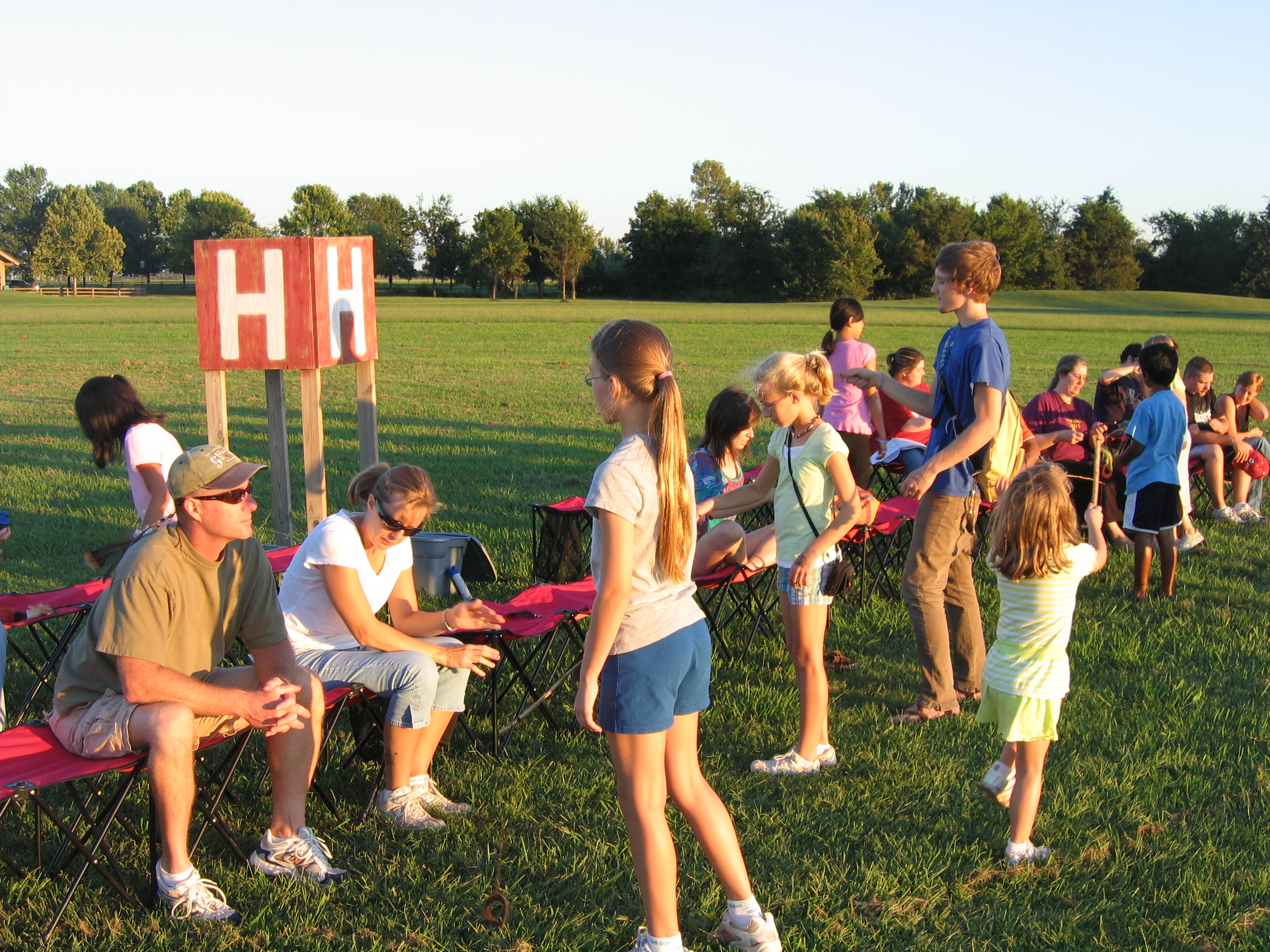 A group of adults and children watching the sunset over Mound B from Mound H.  