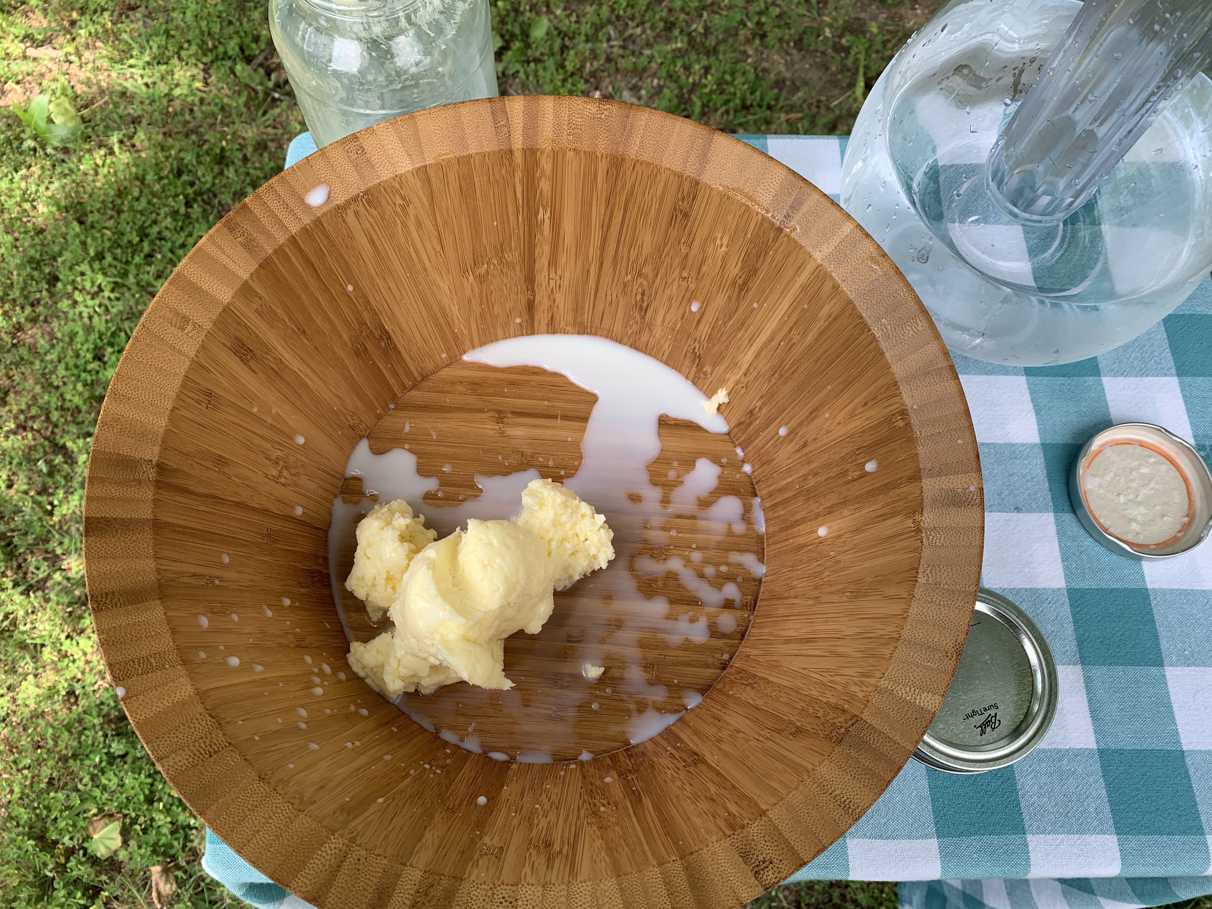 There is a bowl on the table containing a ball of butter that is surrounded by specks of buttermilk