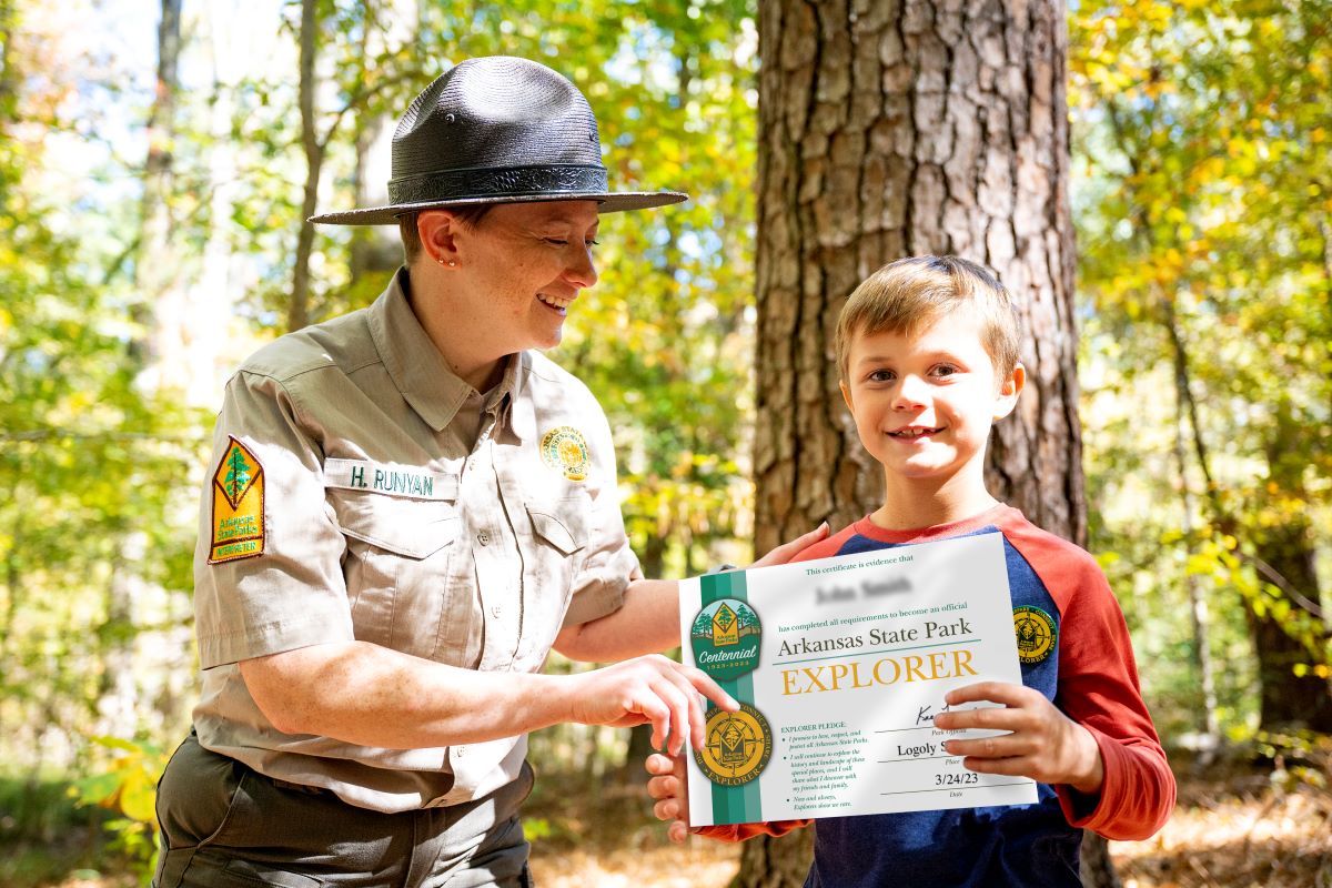 Park interpreter handing a boy a state park centennial certificate