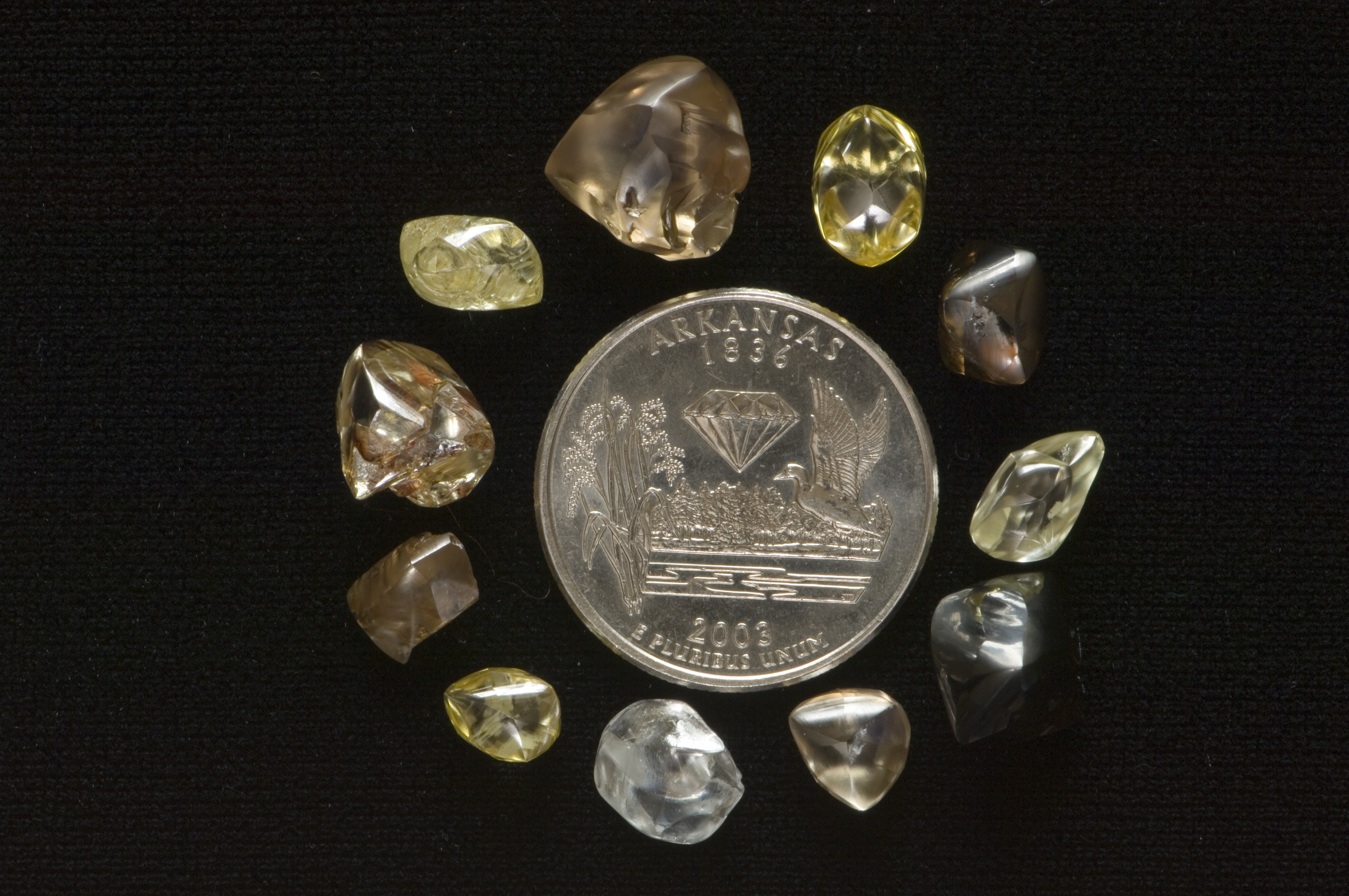 Diamonds found at Crater of Diamonds placed around a quarter to show scale