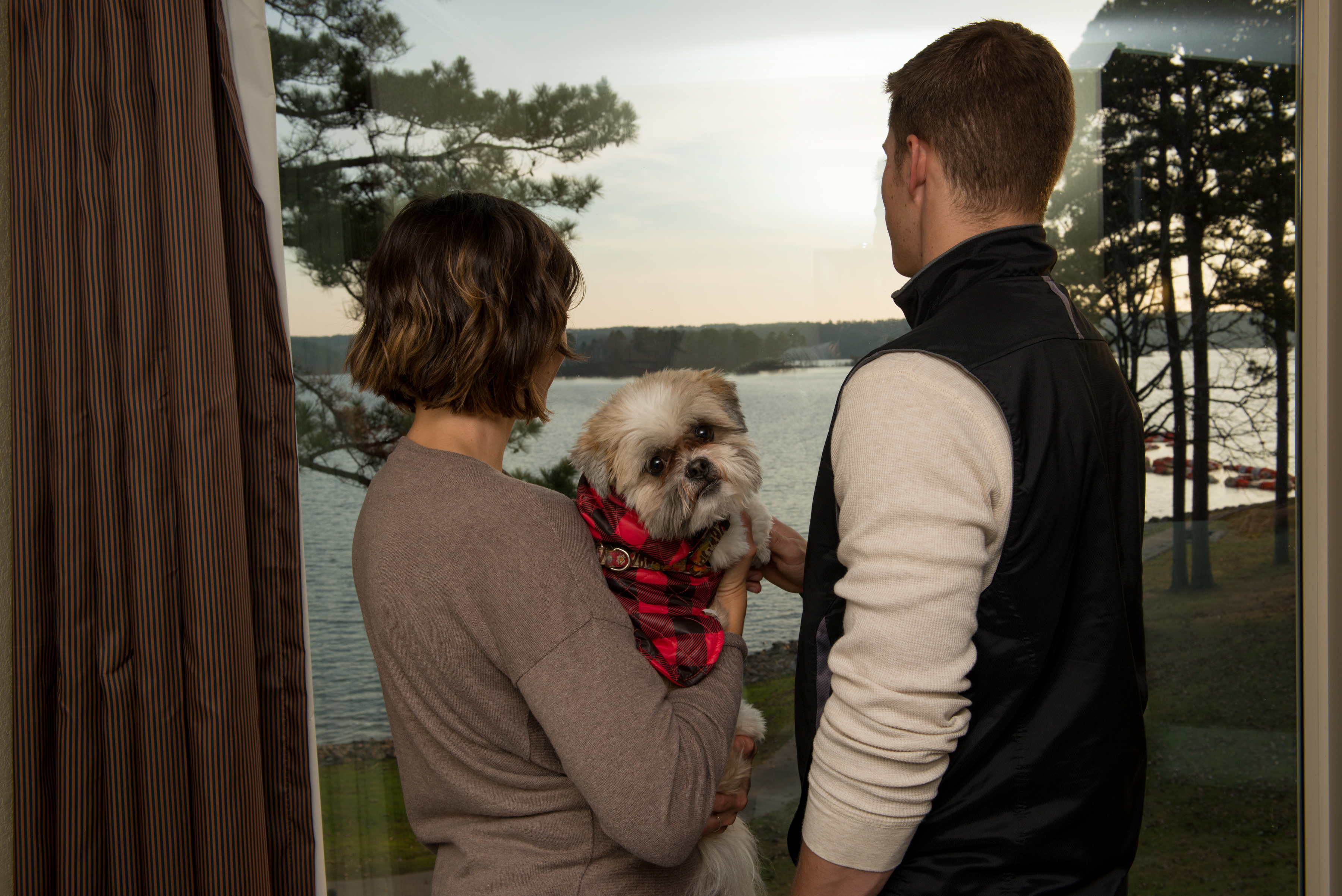 DeGray Lake Resort State Park lodge with couple holding dog looking outside of their room at pool view
