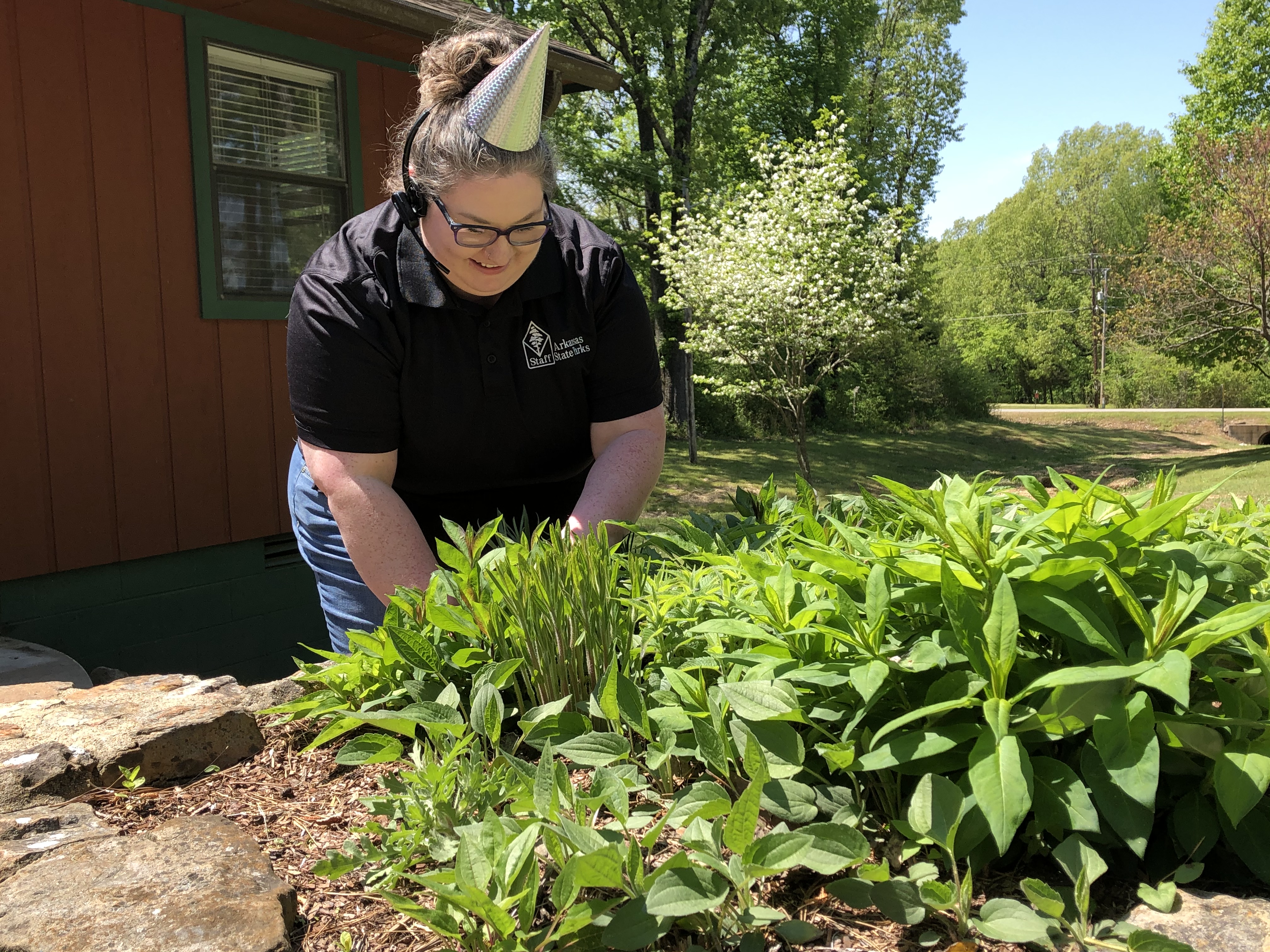 Park employee smiling while tending landscaping bed near visitor center