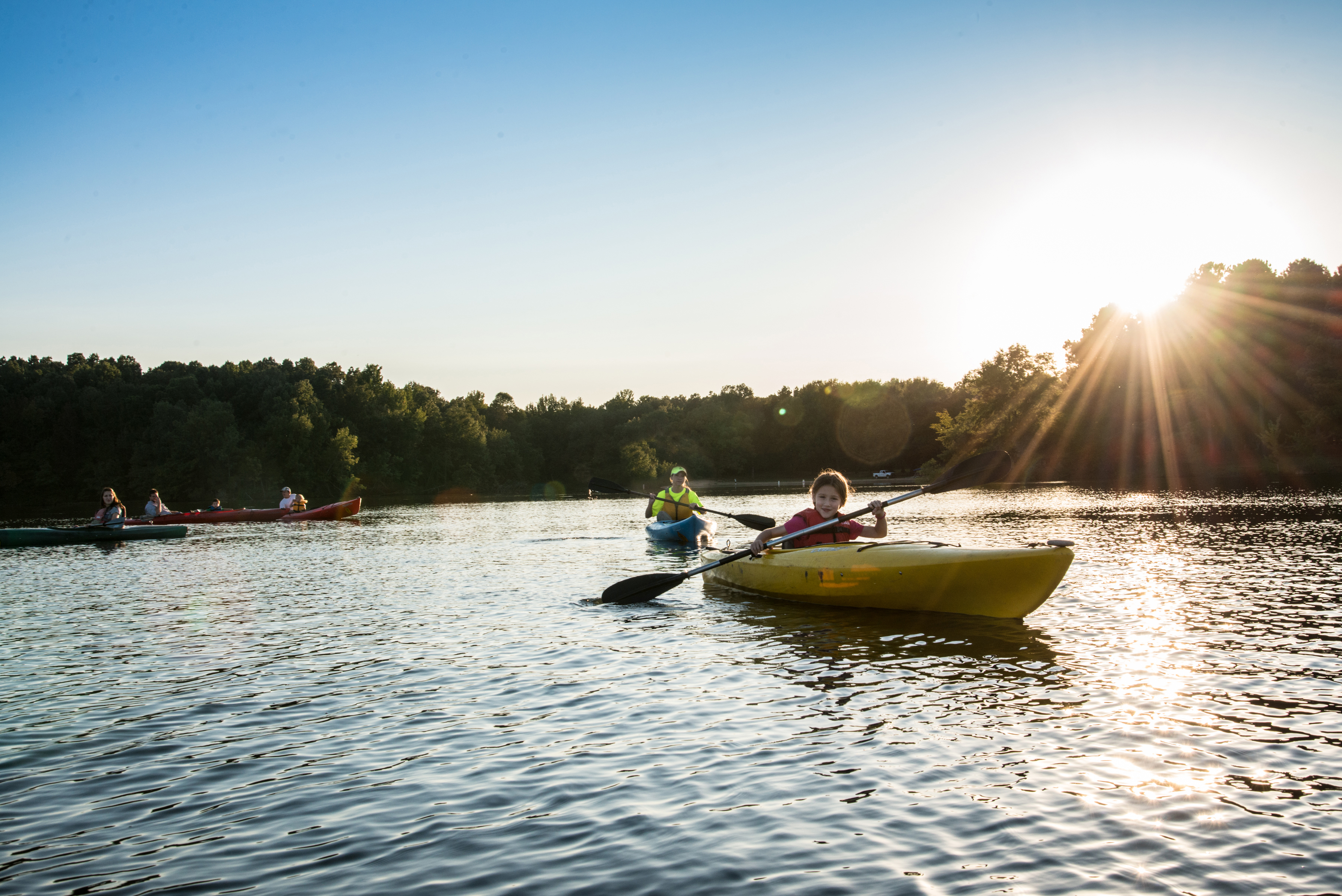 Young girl smiles at the camera while paddling a kayak