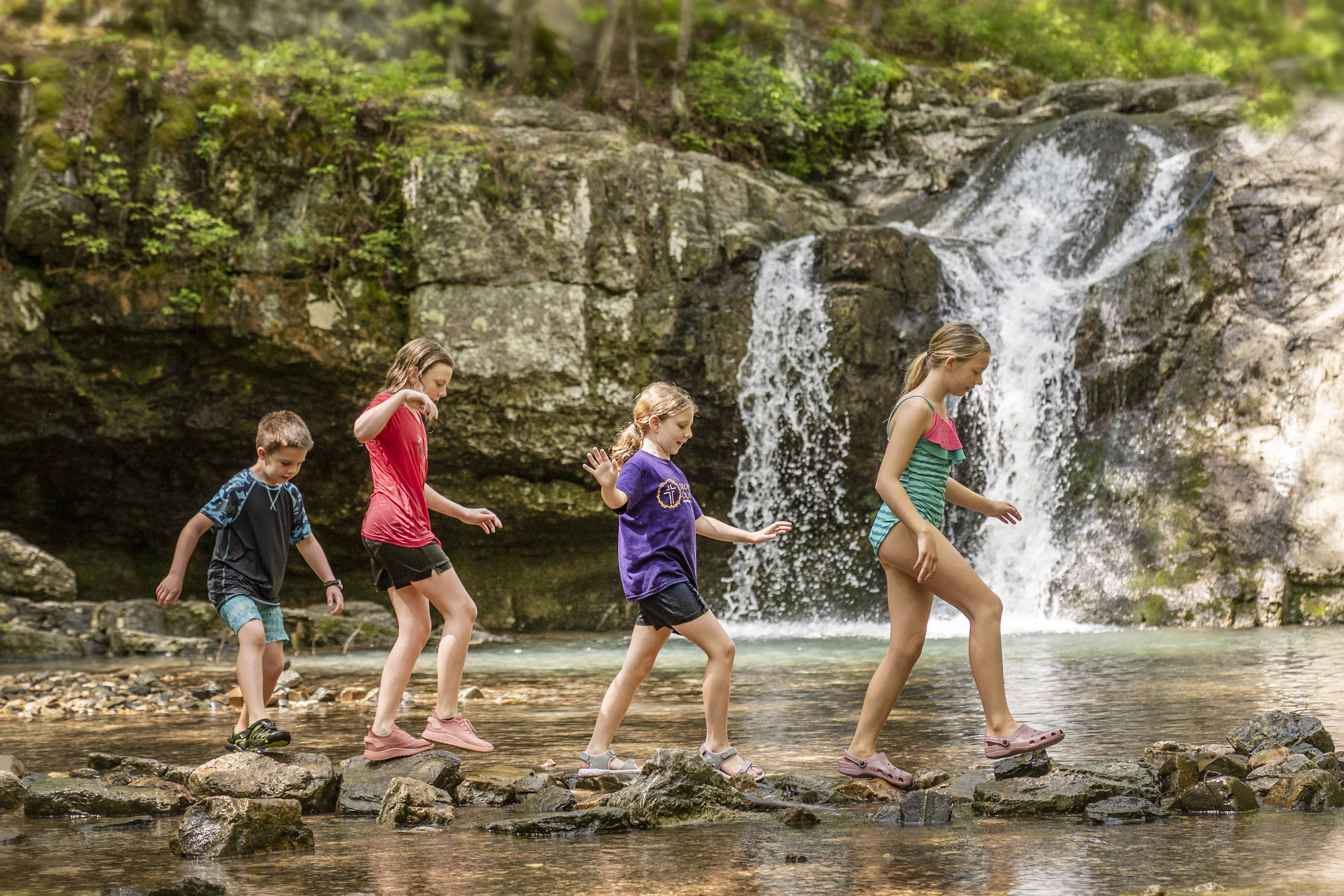 Children walking along the pond with a waterfall in the background