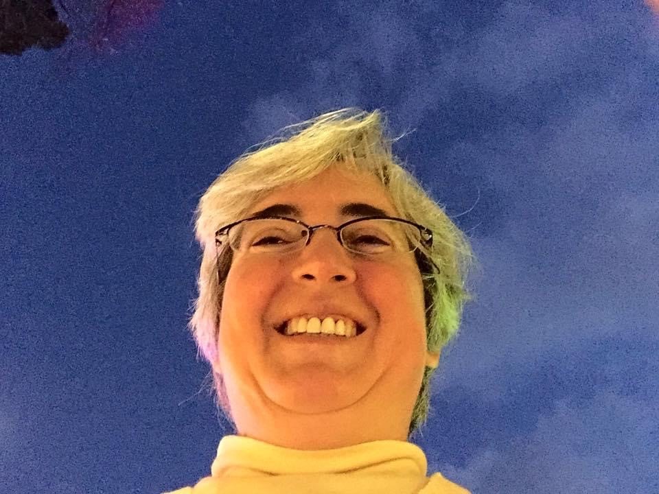 Melanie Thornton smiling with a purplish sky with clouds in the background