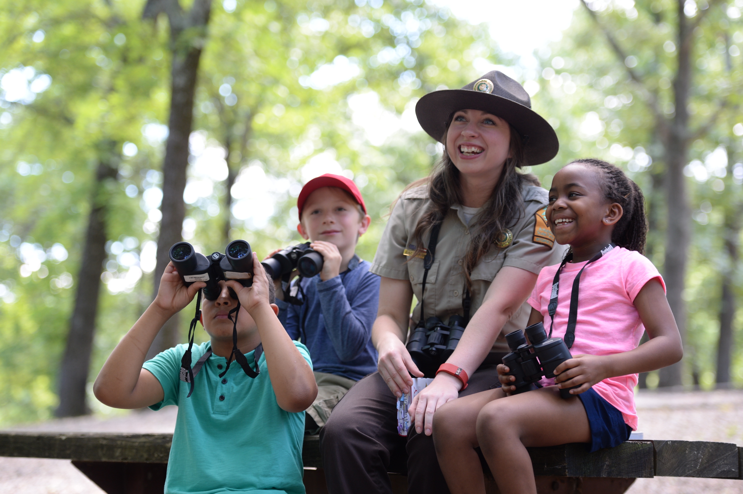 Children and a park interpreter using binoculars to search for birds