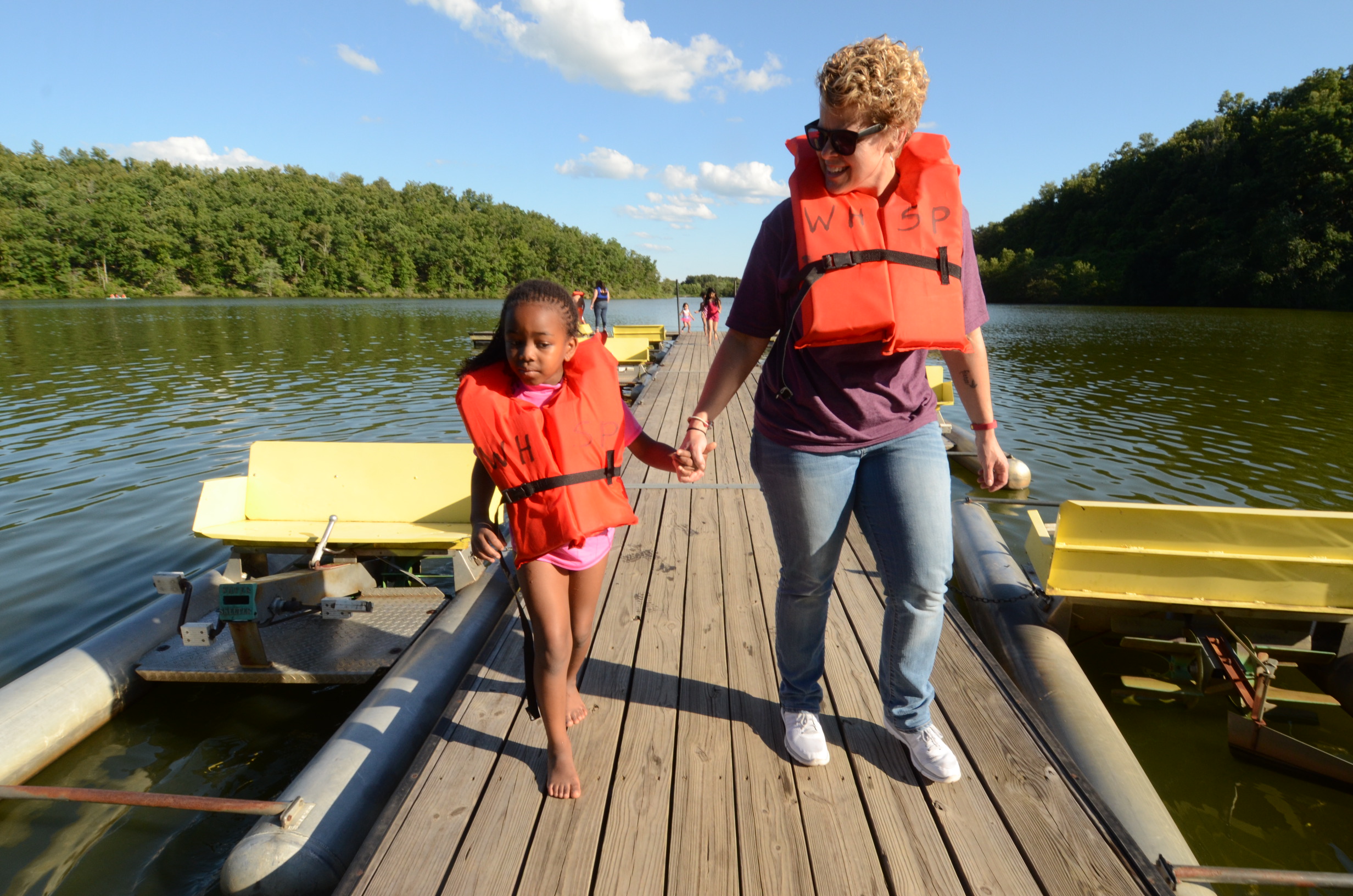 Mother and son wearing lifejackets walking on a wooden dock