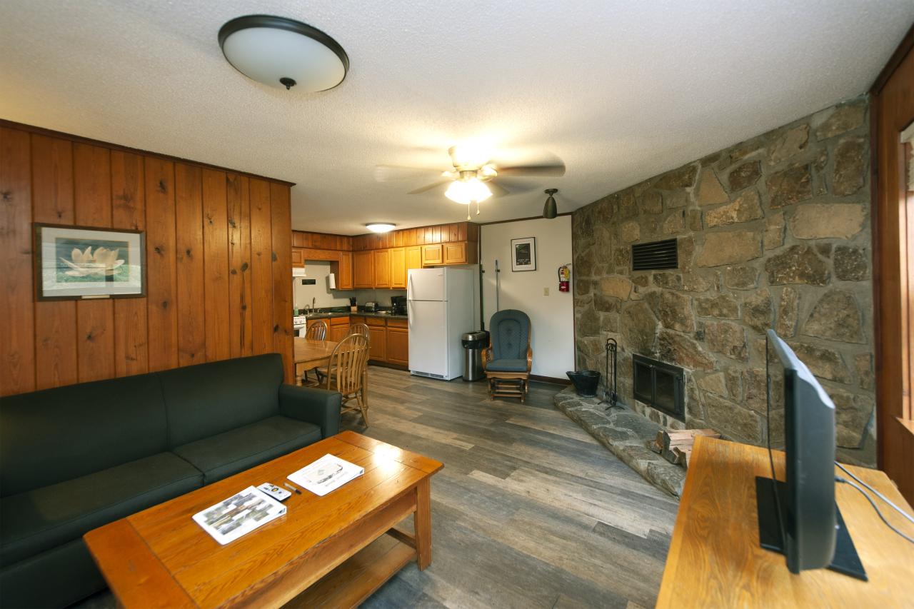 A view of the living room and kitchen, with sitting area, fireplace and full kitchen at Cabin 1 at Crowley's Ridge State Park