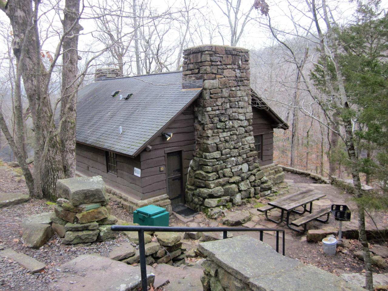 An exterior view of cabin 10 showing a stone staircase leading to the front door and outdoor seating area with picnic table and outdoor grill