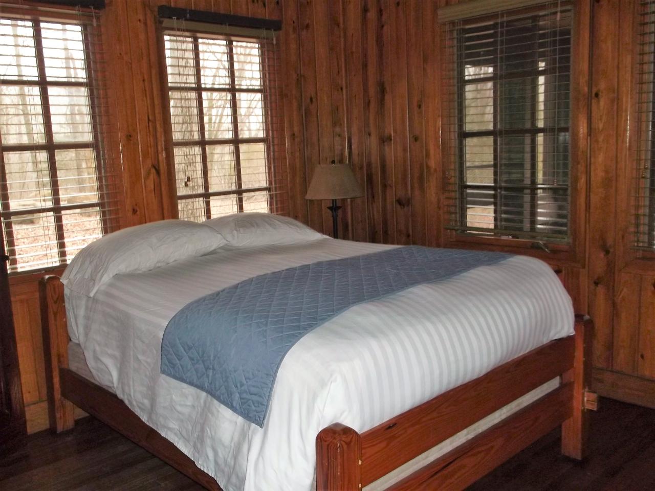 A view of the bedroom in cabin 12 including a bed and two exterior windows
