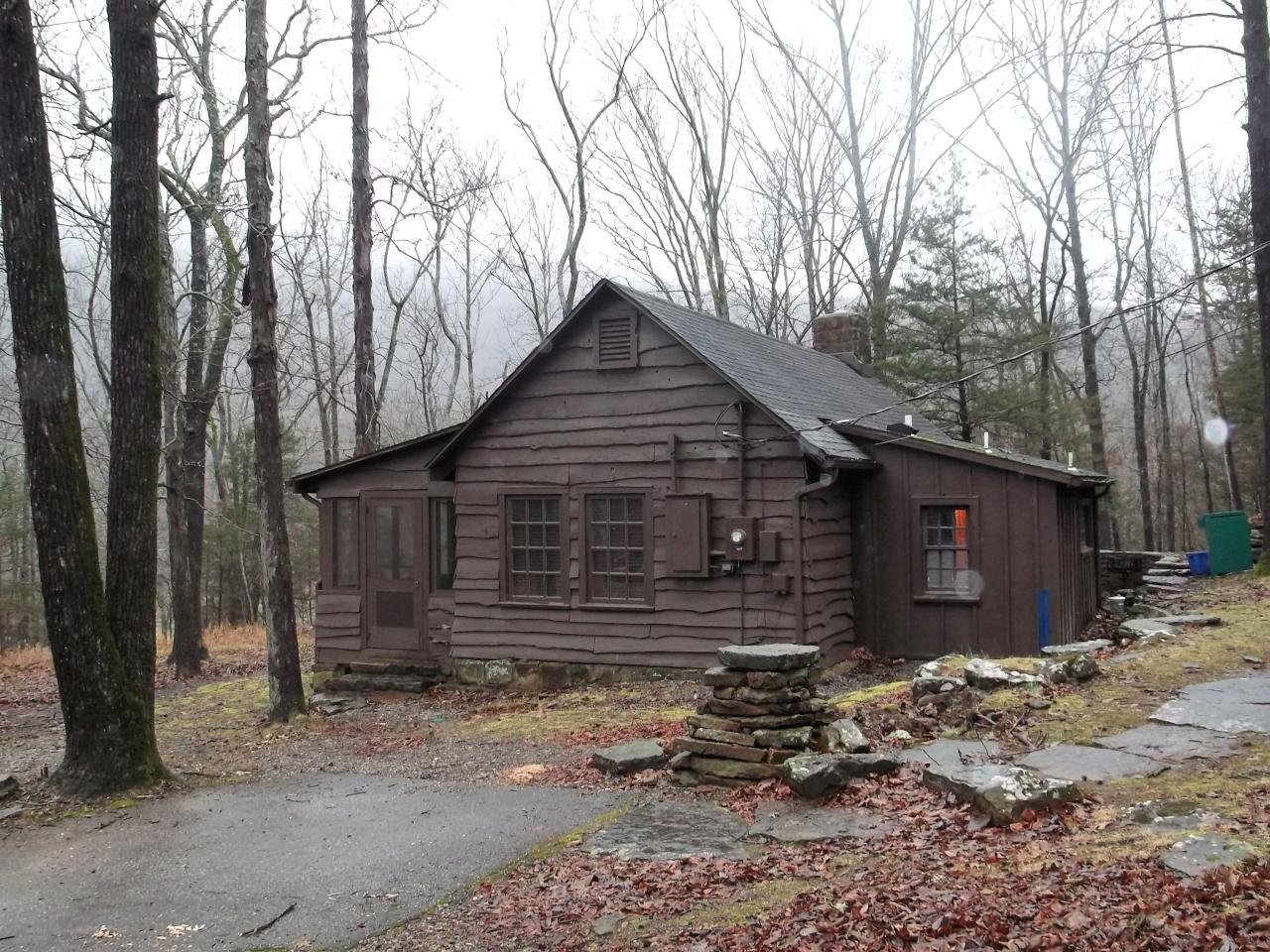 An exterior view of cabin 12 including a parking area and entrance to screened in porch area
