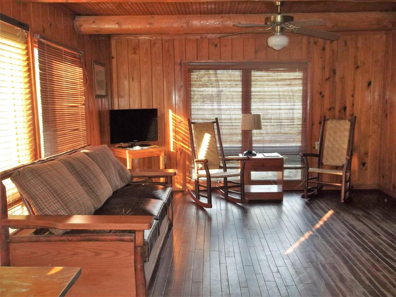 View of the living area in Cabin 2 including a couch, two rocking chairs, a tv and two large windows