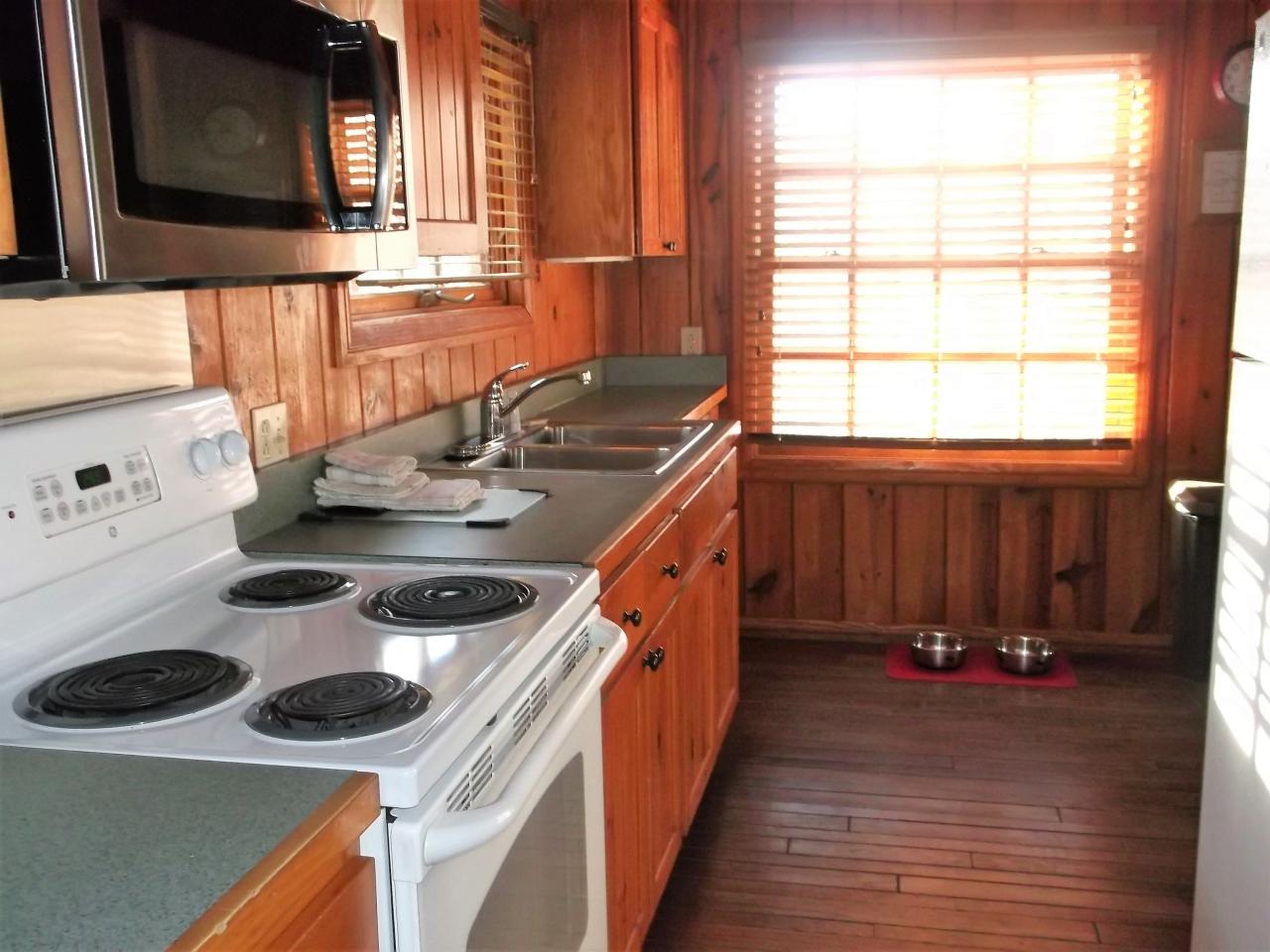 A view of the kitchen in Cabin 2 including an oven, microwave, double sink and refrigerator