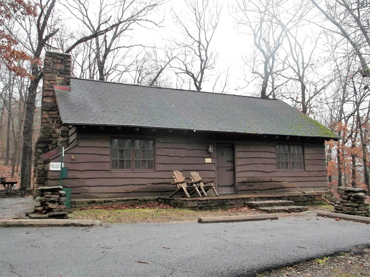 Exterior view of Cabin 5 with front entrance, front porch seating area and parking spaces directly in front of the cabin