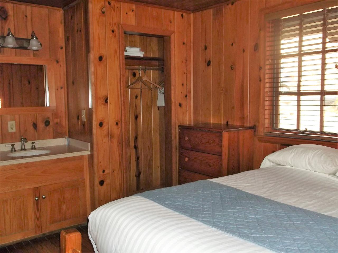 A view of one of the three bedrooms including a bed, dresser, closet and sink area