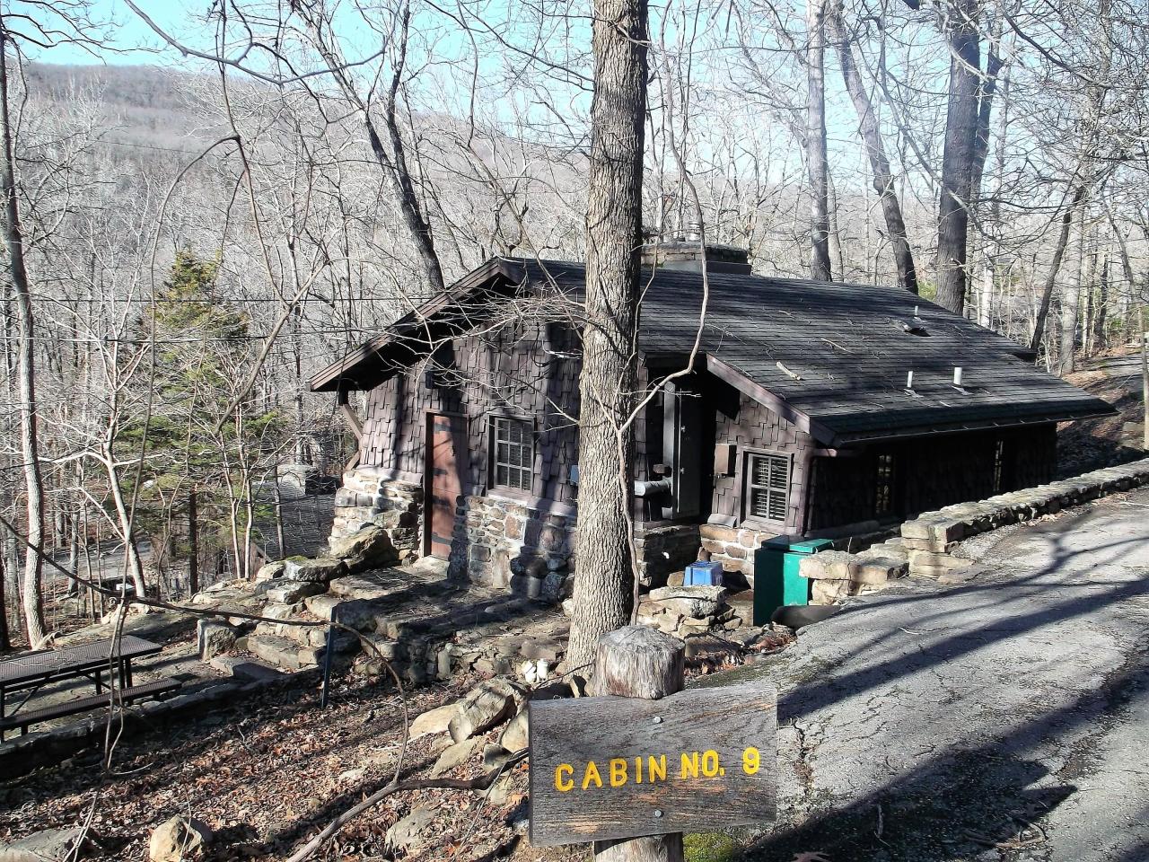 An exterior view of cabin 9 showing a stone staircase to the front entryway as well as an outdoor seating area that overlooks the surrounding view