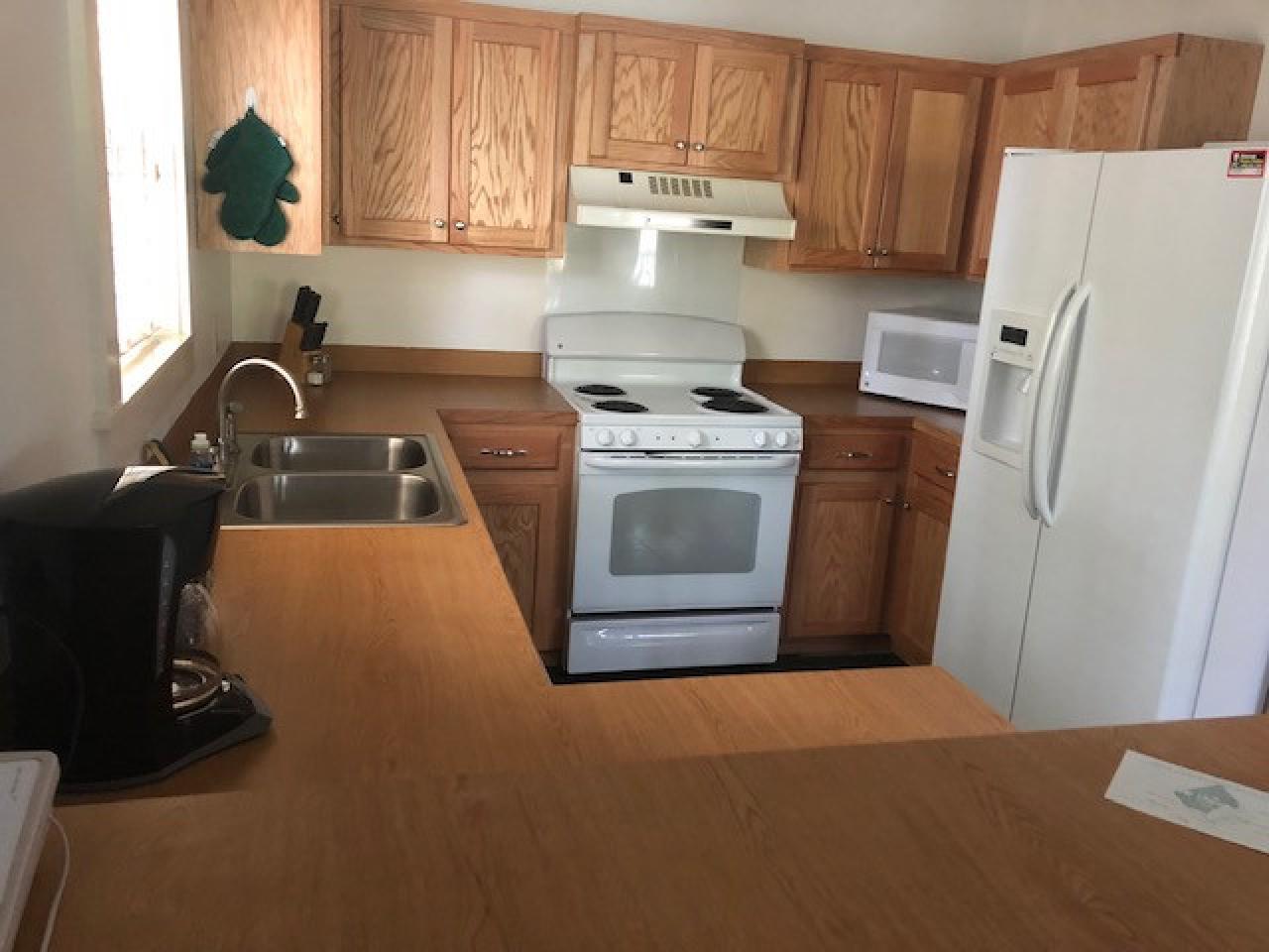 A view of the full kitchen in Cabin 1 at lake Ouachita State Park including a fridge, oven, microwave and coffee maker