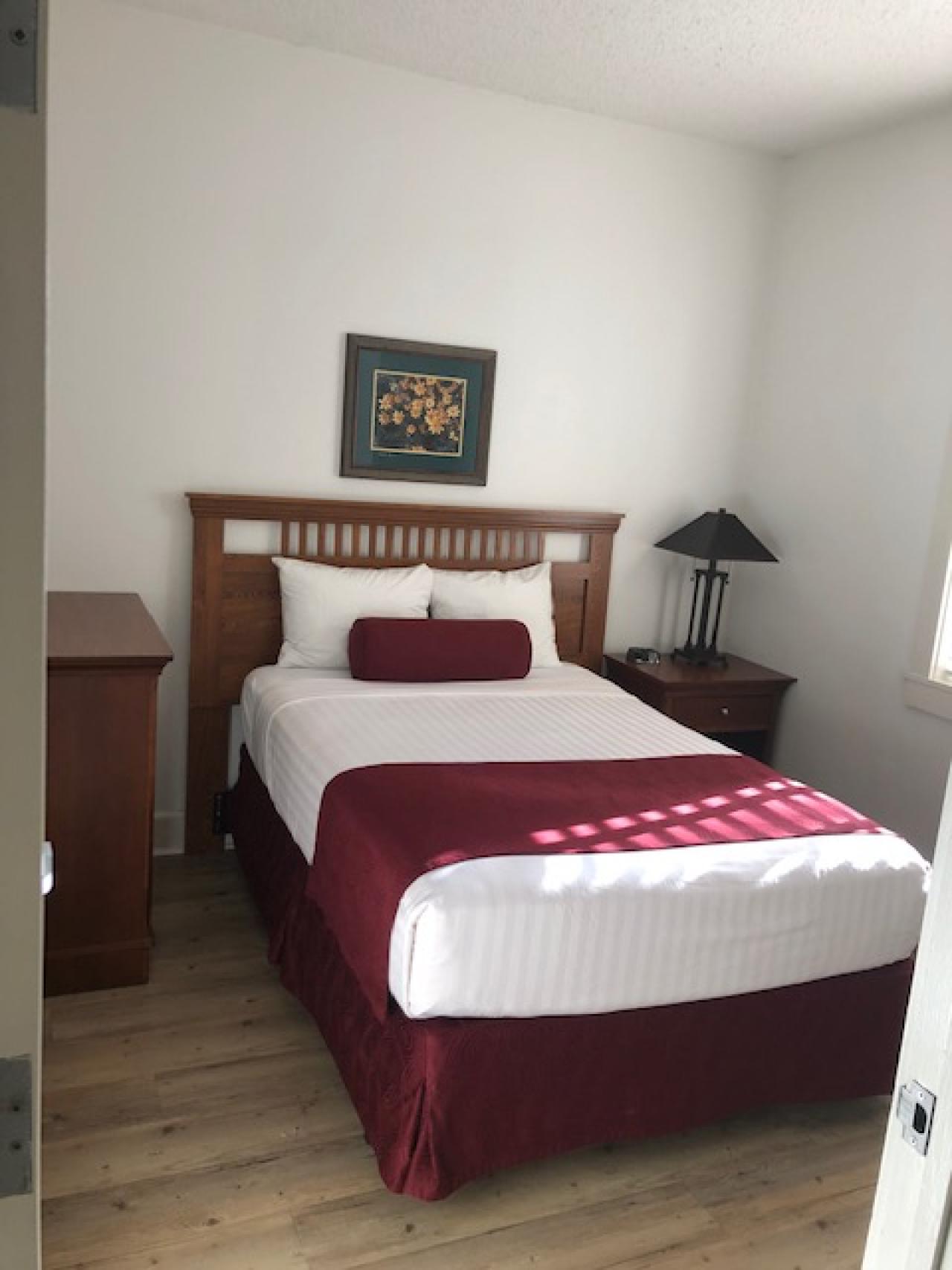 A view of the sleeping area in one of the bedrooms at Cabin 1 at Lake Ouachita State Park including a bed and two side tables