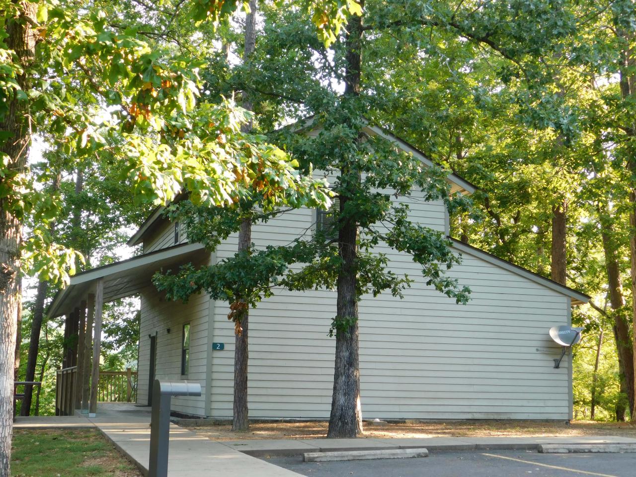 An exterior view of the two-story Cabin 2 at Lake Ouachita State Park including parking spaces and the front porch area