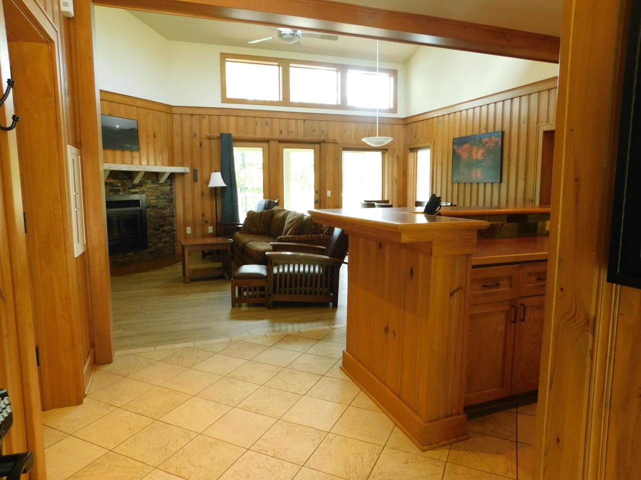 A view of the living room area from the kitchen at Cabin 3 at Lake Ouachita State Park including seating, a fireplace and exteriors doors and large windows