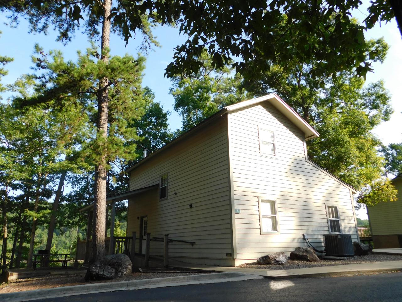 An exterior view of the two-story Cabin 7 at Lake Ouachita State Park including parking spaces and the front porch area