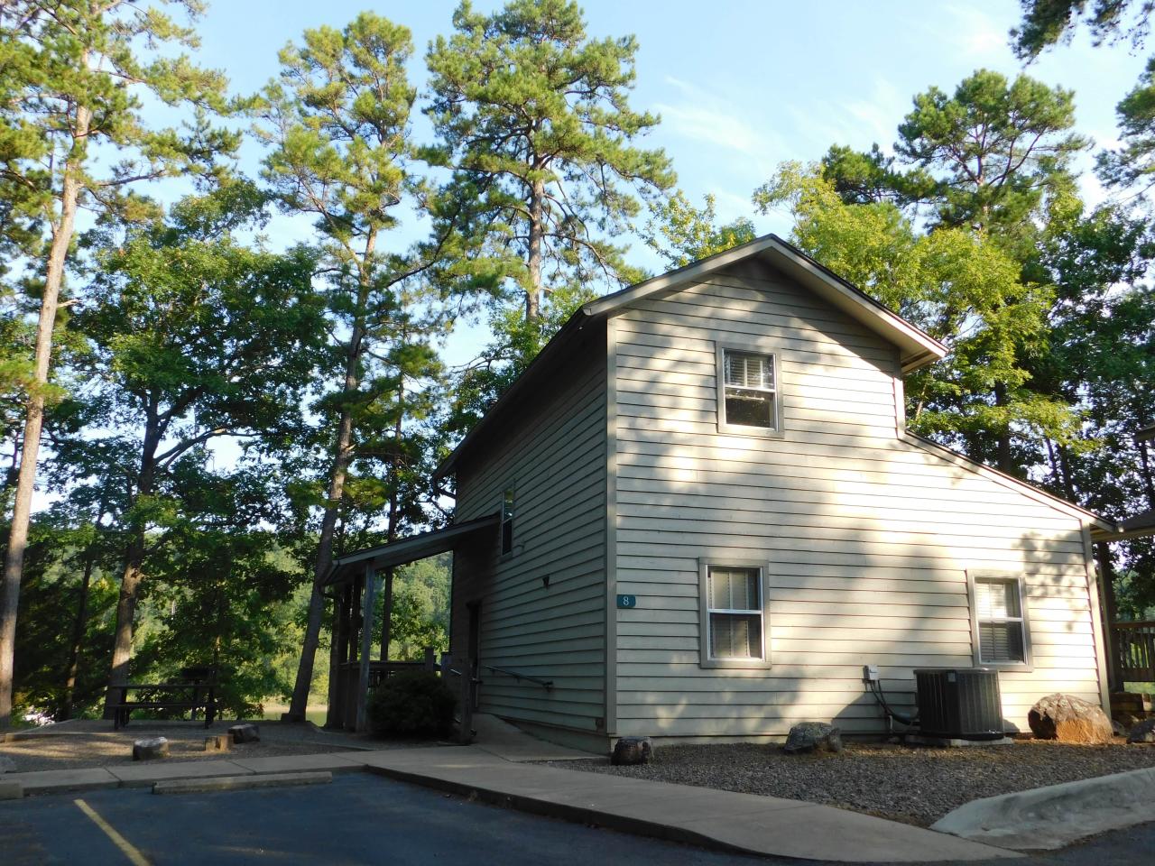 An exterior view of the two-story Cabin 8 at Lake Ouachita State Park including parking spaces and the front porch area