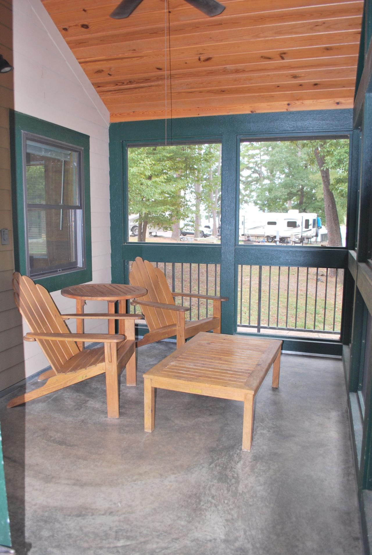 The screened in front porch seating area at Camper Cabin 59 at Lake Ouachita State Park including two chairs and a table