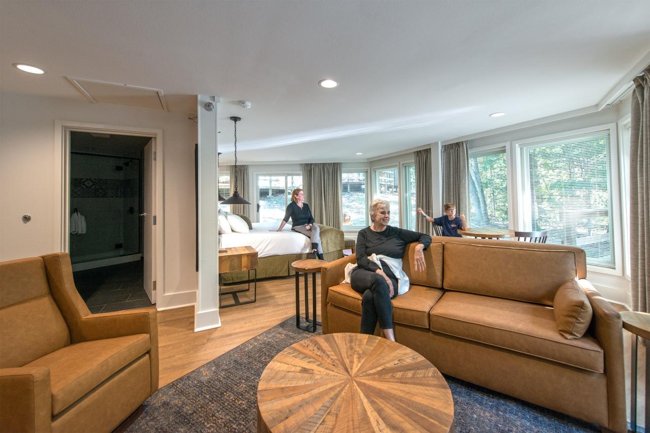 A view of the main living and sleeping area in the King Deluxe Suite including a king bed, seating area and large windows throughout at the Ozark Folk Center State Park