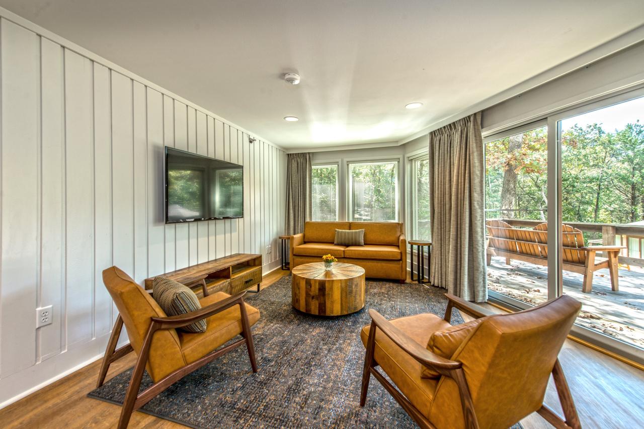 A view of the living area of the standard suite including a pull-out couch, two chairs, coffee table and TV