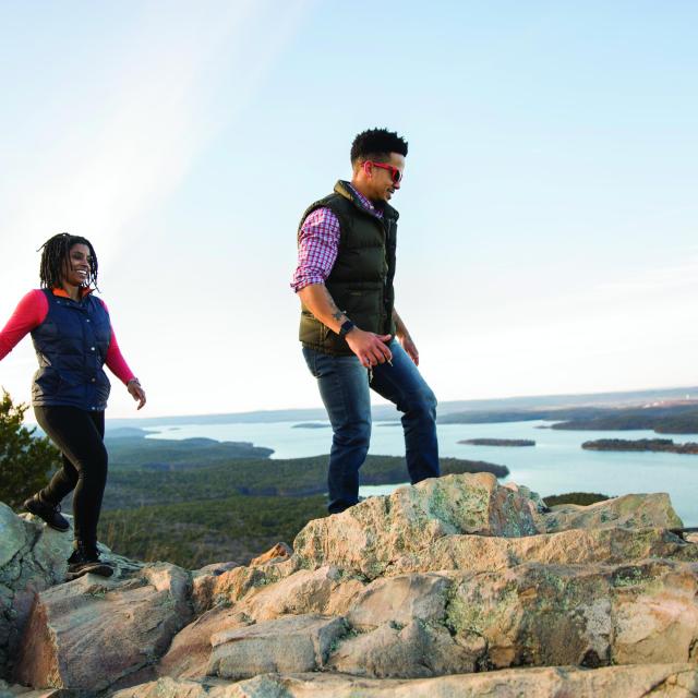 Three people hiking Pinnacle Mountain with the Arkansas River in the background