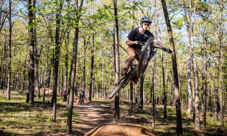 A mountain biker doing a jump on the Pinnacle Mountain State Park Monument Trails