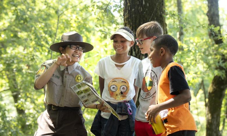 Park interpreter leads a program of children outside at Cane Creek State Park