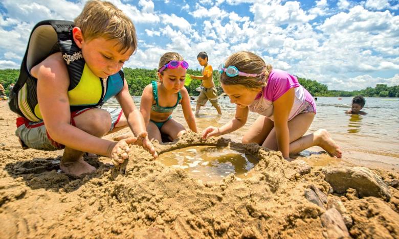 A group of children build a sand castle on the swimming beach