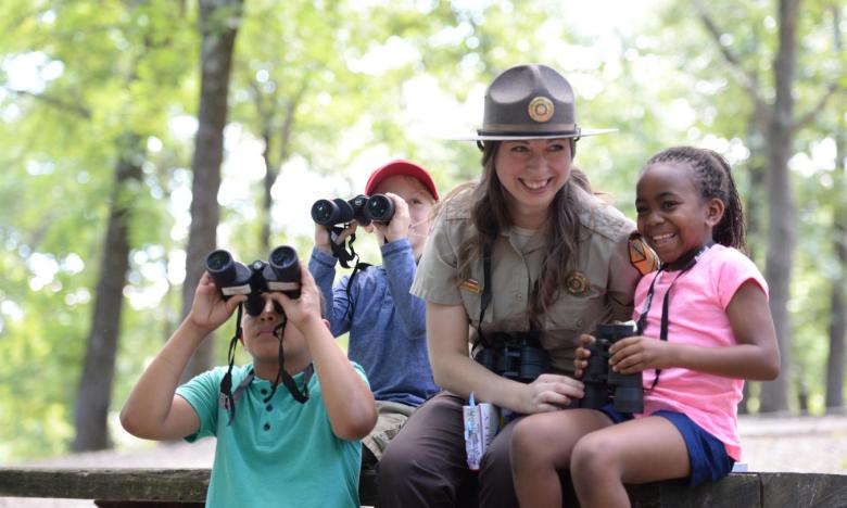 A park interpreter shows a group of children how to birdwatch