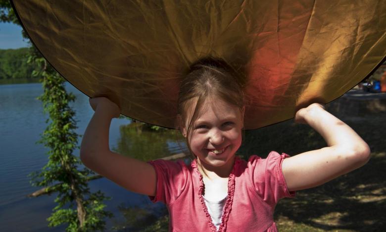 A young girl carries a canoe over her head