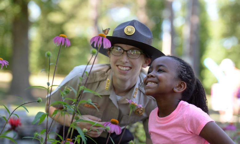 A young girl and a park interpreter staring at a plant
