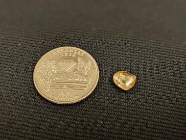 Picture of Christian Liden's Washington Sunshine yellow diamond next to a quarter for scale