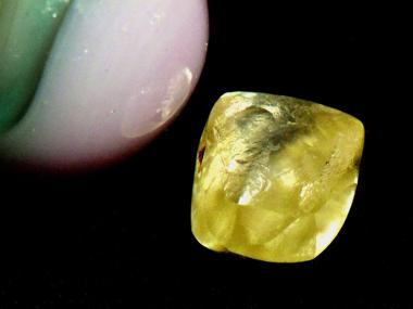 Noreen Wredberg's yellow diamond sitting next to a marble for scale