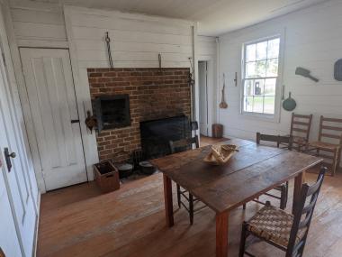 Front room of Sanders kitchen at Historic Washington State Park. There is a table and coal fireplace.