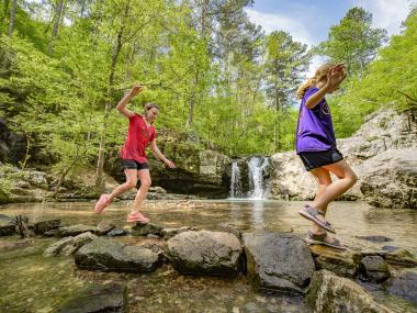 Children playing at the Lake Catherine waterfall on the Falls Branch Trail