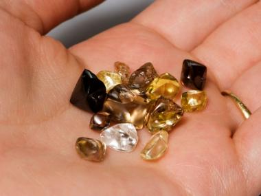 Someone holding white yellow and brown diamonds found at Crater of Diamonds State Park in their hand